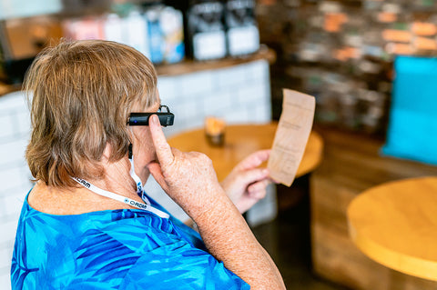 Woman in cafe using OrCam MyEye to read the menu