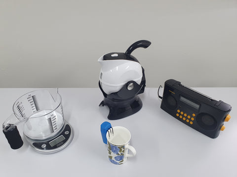 Daily living aids displayed on a desk including jug, radio and talking scales