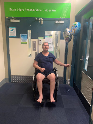 Shaun in wheelchair at Rehab Unit holding balloons