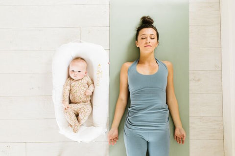 Mother doing yoga while her baby is lounging on a DockATot