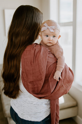 mother carrying a baby in a little unicorn swaddle