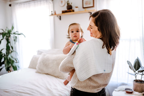 mother burping the baby using a little unicorn burp cloth