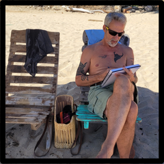 man in beach chair drawing in sketchbook