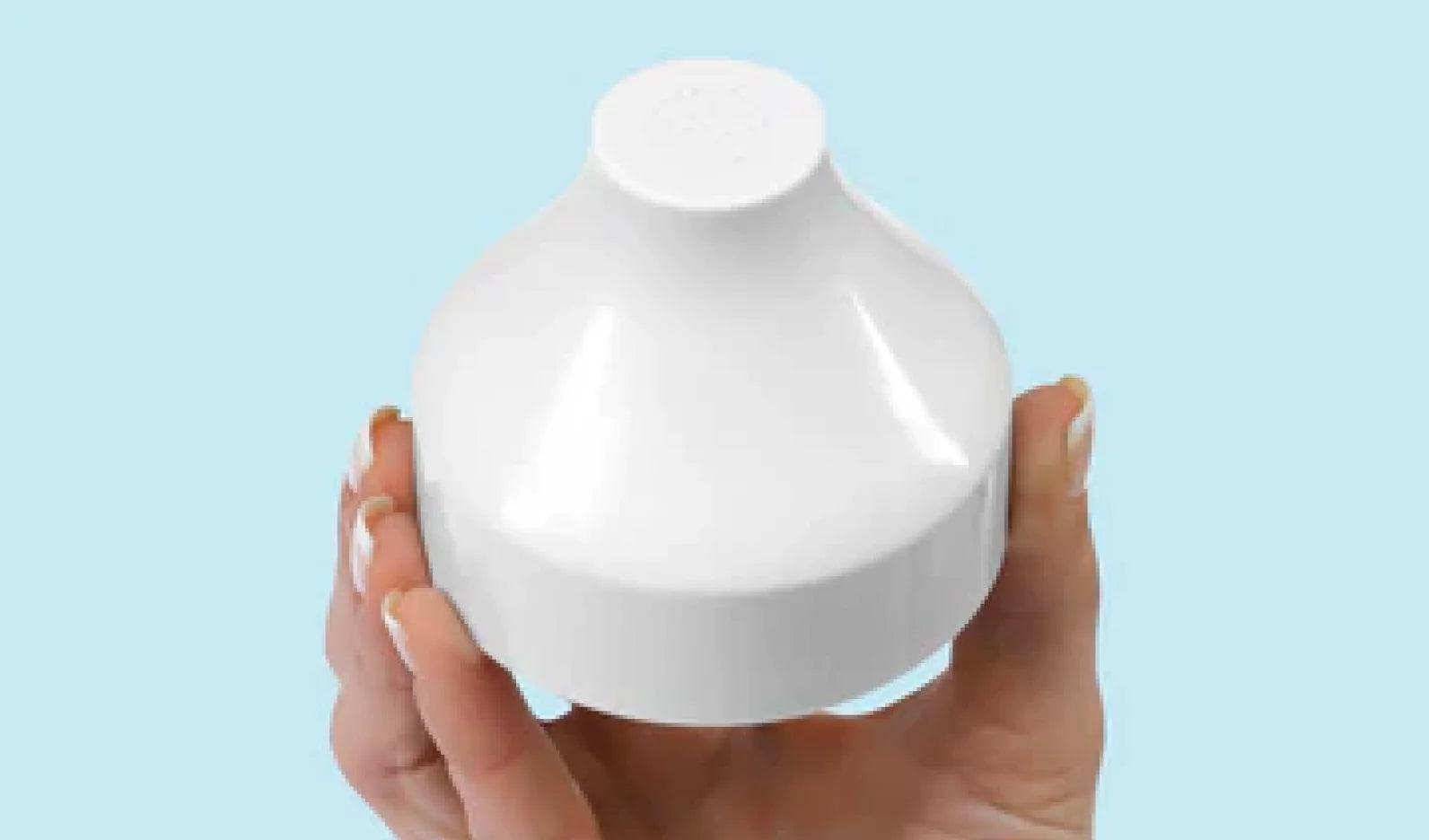 White dome-shaped object held in hand against a blue background.