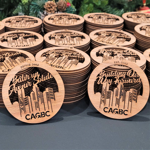 Multiple wooden ornaments laser-cut with Theatre Calgary's logo by LightBurnDesign.