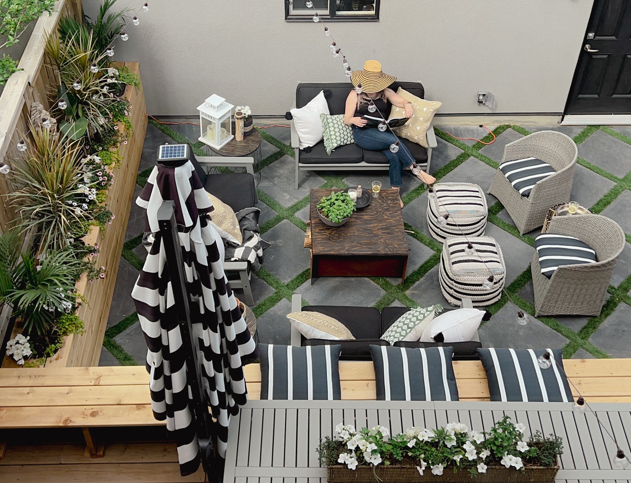 Heather Draper in her outdoor living room "the oasis" featuring diamond pavers with artificial grass. furnishing from ikea and 2022 outdoor decor trend ideas and outdoor styling tips