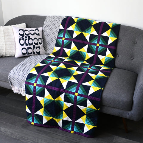 Solar Wind quilt on a sofa next to a pillow that says "good vibes only"