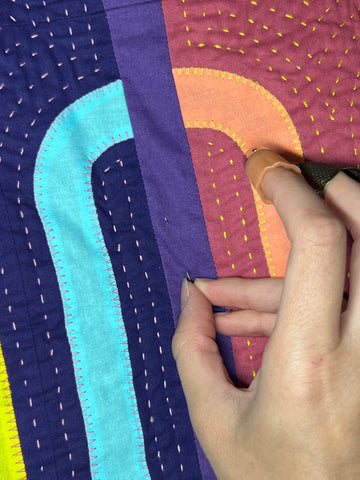 A needle is being inserted into a quilt.