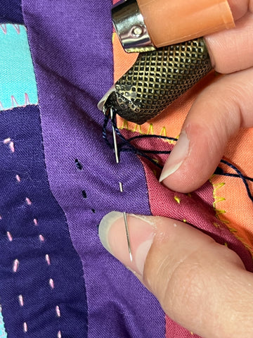 Two stitches are being made through the quilt.