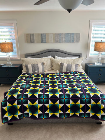 Solar Wind quilt on a king sized bed in a beige bedroom.