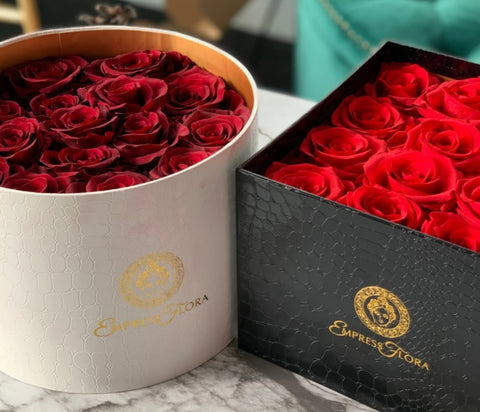 picture of white circle container and a black box containing a bouquet of preserved red roses