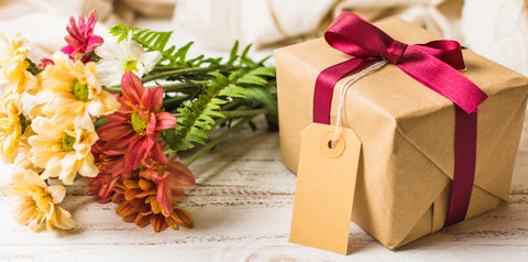 present box with brown tag and flower in bunch table