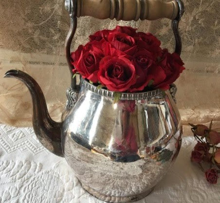 teapot filled with red roses
