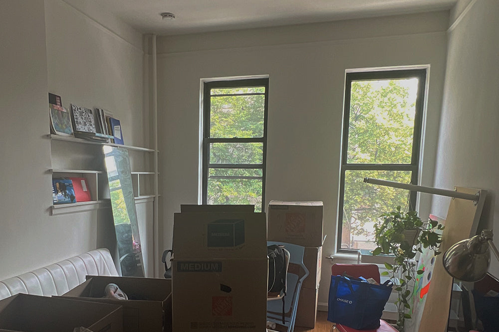 Home office with unpacked boxes and view of trees.