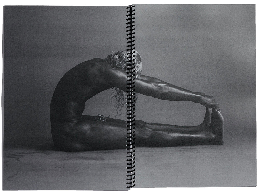 Double page spread showing a monochrome image of a naked man in a yoga posenaked