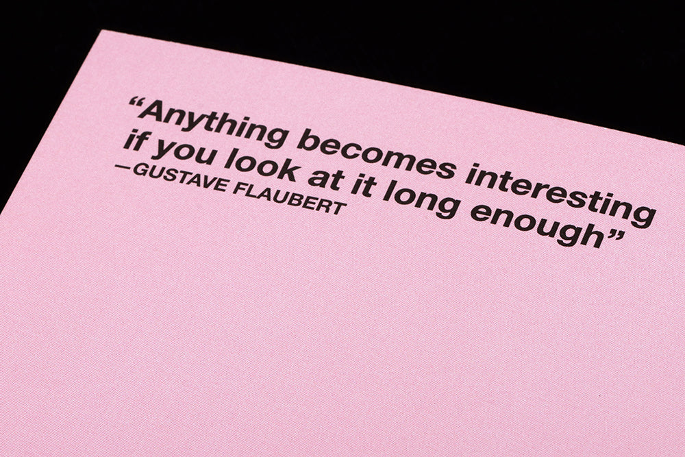 A pink page with black text that says "'Anything becomes interesting if you look at it long enough' Gustave Flaubert"