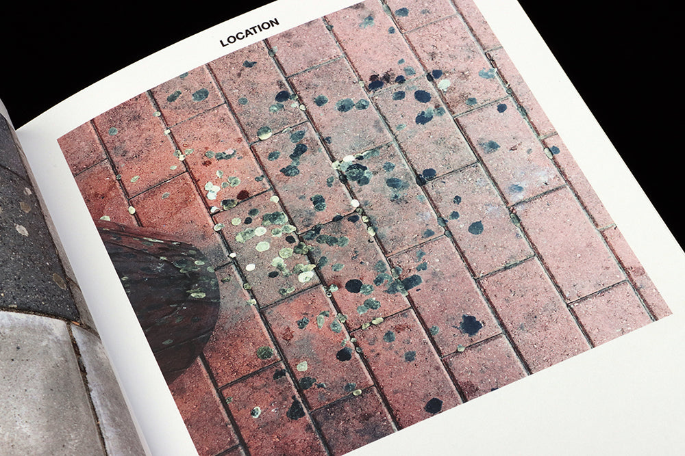 Magazine open at a page featuring a pavement covered in black and grey pieces of old chewing gum