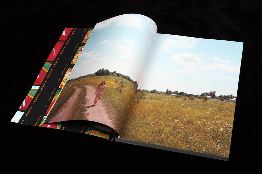 Young girl in swimsuit wanders along country road under a summer blue sky.