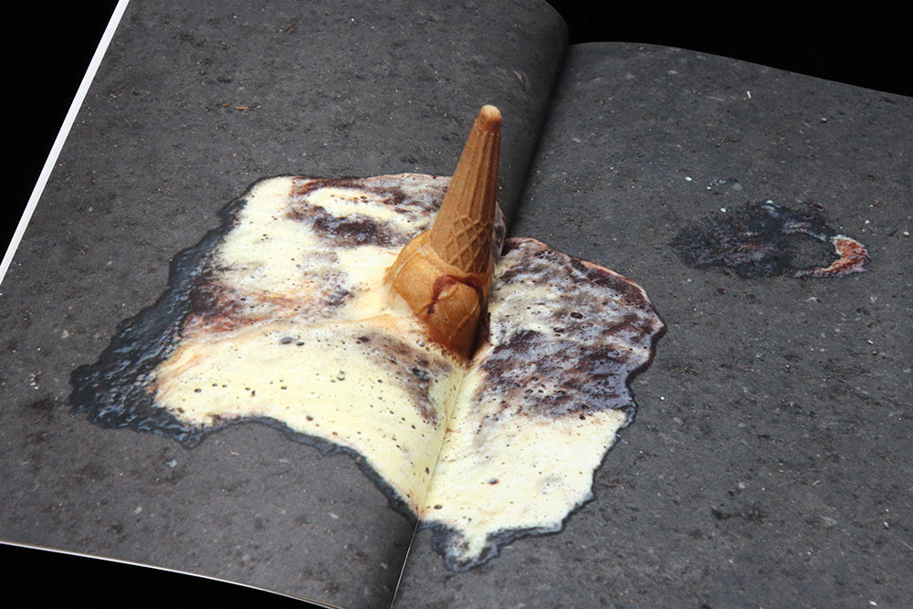 An ice cream cone sits updise down on a street, the ice cream meltinga round it.