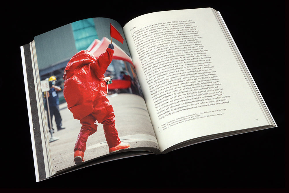 A double-page spread from Vestoj issue 11; on left, a figure walks in a bright red biohazard suit. To right, text
