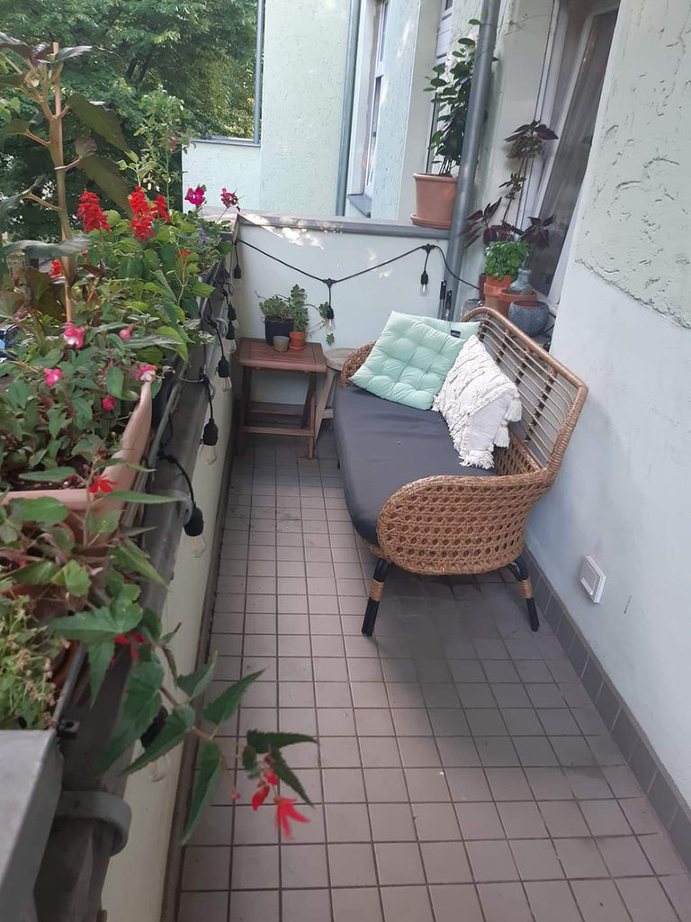 Outdoor balcony with couch and flowering plants.