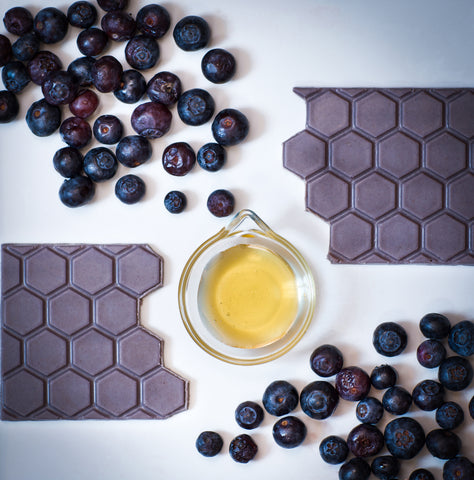 A honeymoon Chocolates bar is sitting next to a cup of honey and blueberries