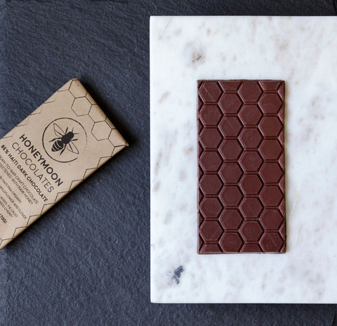 A photo of Honeymoon Chocolate's Haiti Chocolate bar on a slab of marble with is wrapper next to it