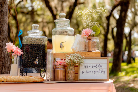 table avec de grandes jars remplies de boissons et des fleurs