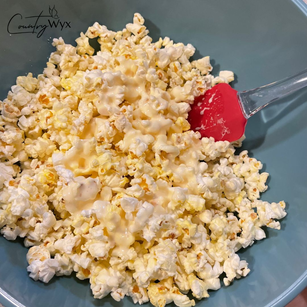 Spooky Scarecrow Popcorn - stirring the marshmallow mixture with popcorn