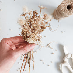 Adding whimsical flower to a dried flower posy.