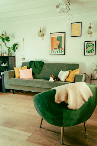 interieur met groene zetels, kaders met prenten en planten
