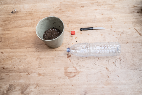 Lege plastic fles met dop, aardappelmes en zaai- en stekgrond