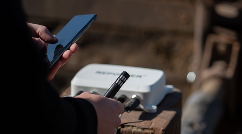 A Reporter with relative humidity sensor lies on a wall while a person holds a smartphone