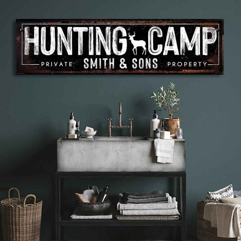 Hunting Decor of a black sign with the words Hunting Camp and family name