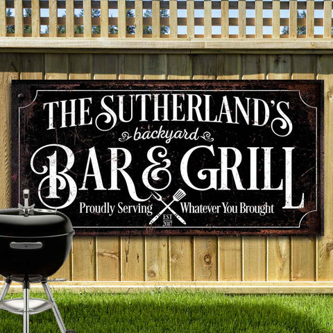 Personalized bar & grill sign with family name. Black canvas or metal backdrop with ornate white font. Sign reads "proudly serving whatever you brought." 