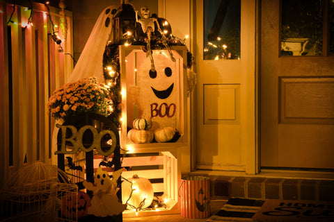 Halloween front porch decor. Skeletons with cute ghosts  and pumpkins on doorsteps. 