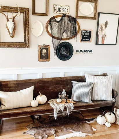 Modern farmhouse Halloween entryway display. Bench with modern farmhouse pillows and pumpkins with spooky wall decor.