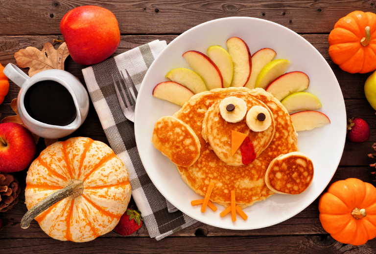 plate of pancakes garnished like a turkey with apples and bananas and Mr.Sticks Breakfast Seasoning with Cinnamon and Sugar