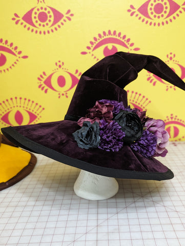Finished slouchy witch hat decorated with dried flowers on a wig stand.