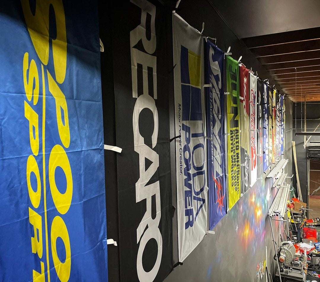 Spoon, Recaro, TODA, Signal, and more nobori flags hanging on a garage wall