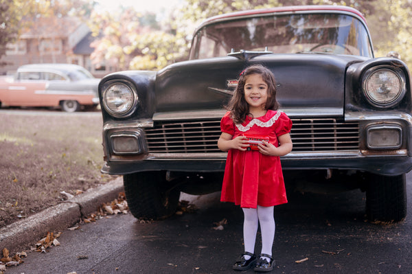 Girl in red velvet dress by vintage car