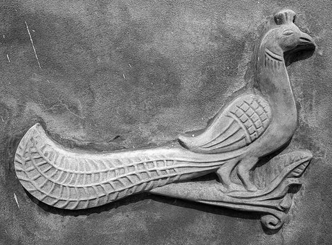 textured grey stone peacock carving on wall in India