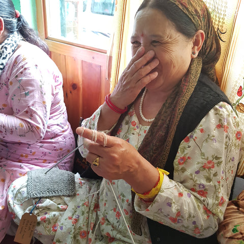 artisan woman in India giggles while knitting