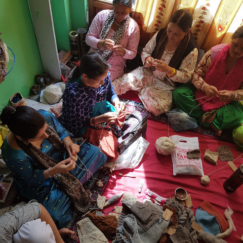 group of artisan women in India knit together surrounded by pure wool 