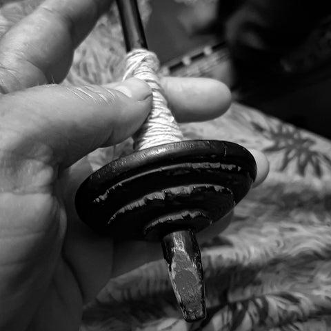 hand holds wooden masayan spindle for plying yarn in Himachal Pradesh India