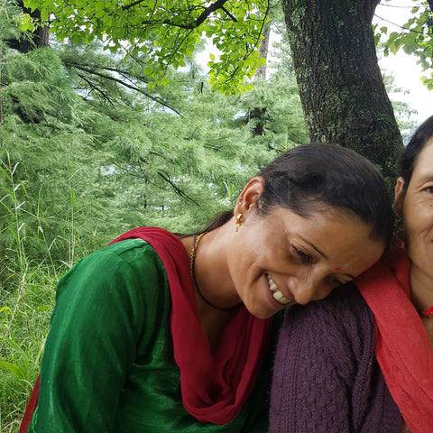 artisan woman in India leans on friend's shoulder smiling