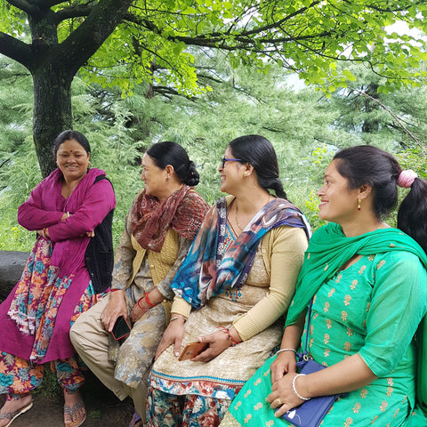 artisan women in bright clothing in India sit and chat together