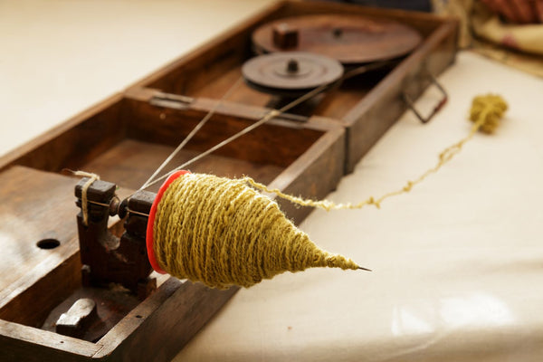 yellow naturally dyed yarn on a peti charkha spinning wheel in India