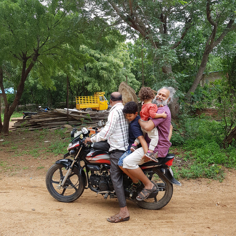 a family sits on the back of a motorcycle in india
