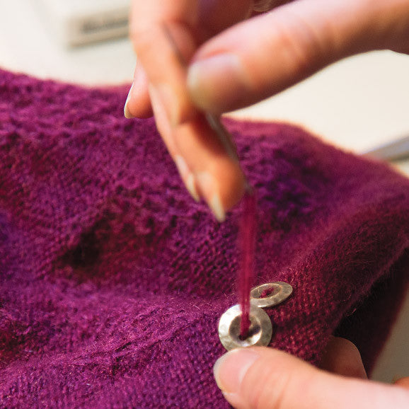 Hand sewing buttons onto a hat.